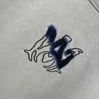Light gray crewneck T-shirt close-up of navy logo embroidery