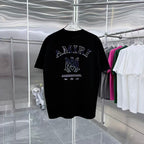 Black crew-neck T-shirt with AMIRI graphic and small text below