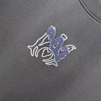 Close-up of blue-and-white horse emblem on dark crew-neck T-shirt