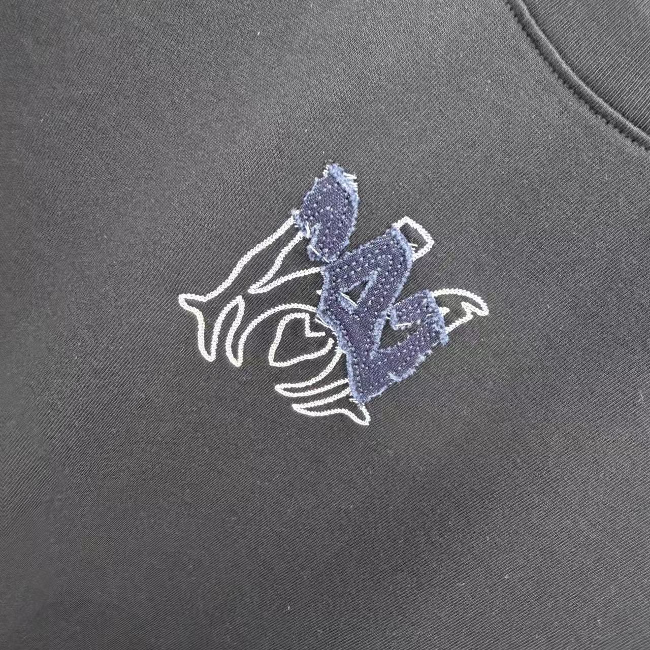 Close-up of blue-and-white horse emblem on dark crew-neck T-shirt