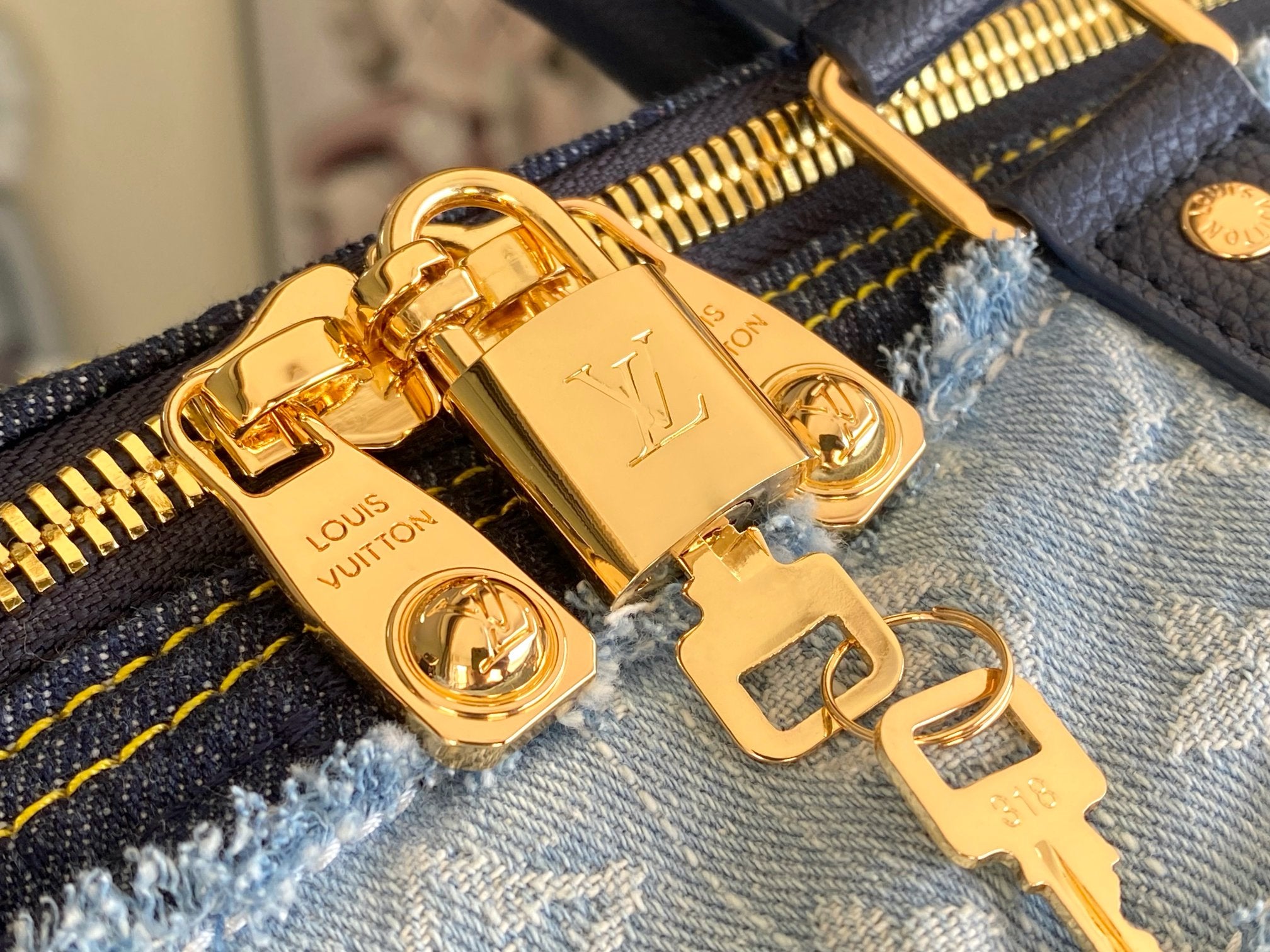 Blue patchwork denim bag close-up of gold logo plate and clasp hardware