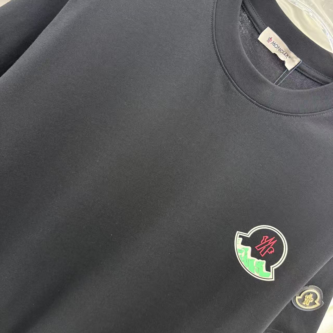 Black short-sleeve T-shirt chest area with crest patch and fabric texture
