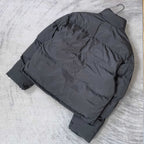 Long puffer jacket in dark gray, laid flat, showing quilted panels and hood
