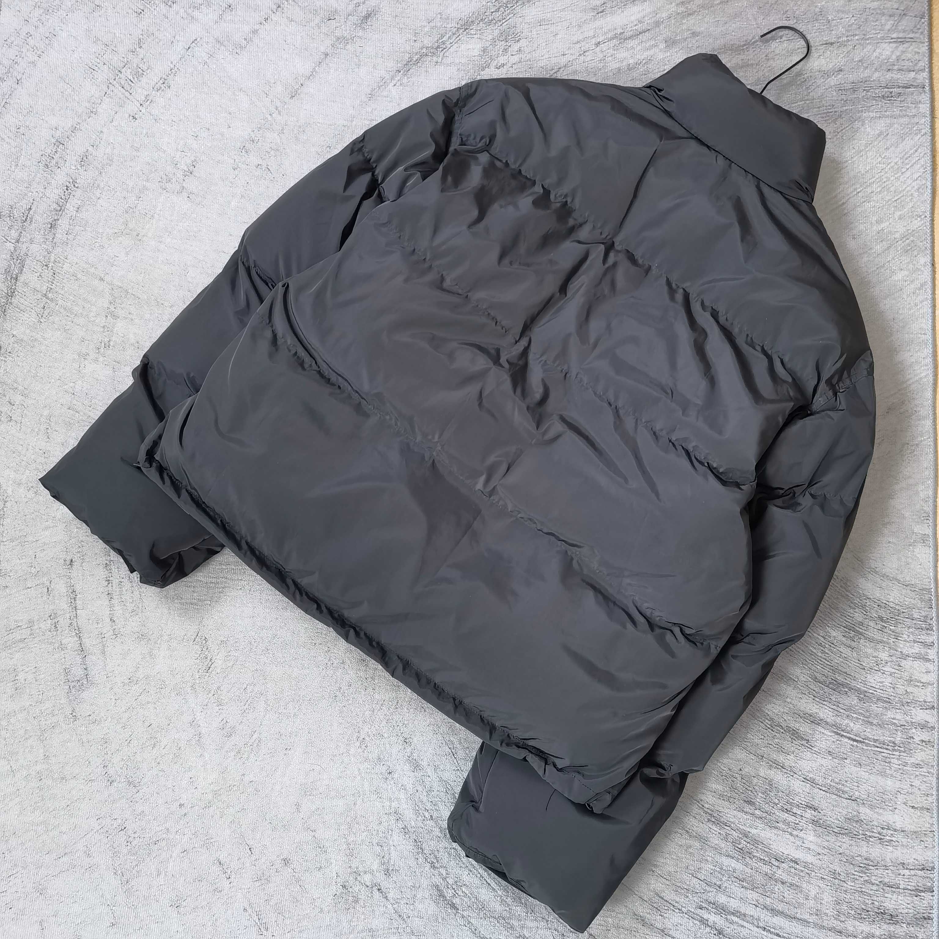 Long puffer jacket in dark gray, laid flat, showing quilted panels and hood
