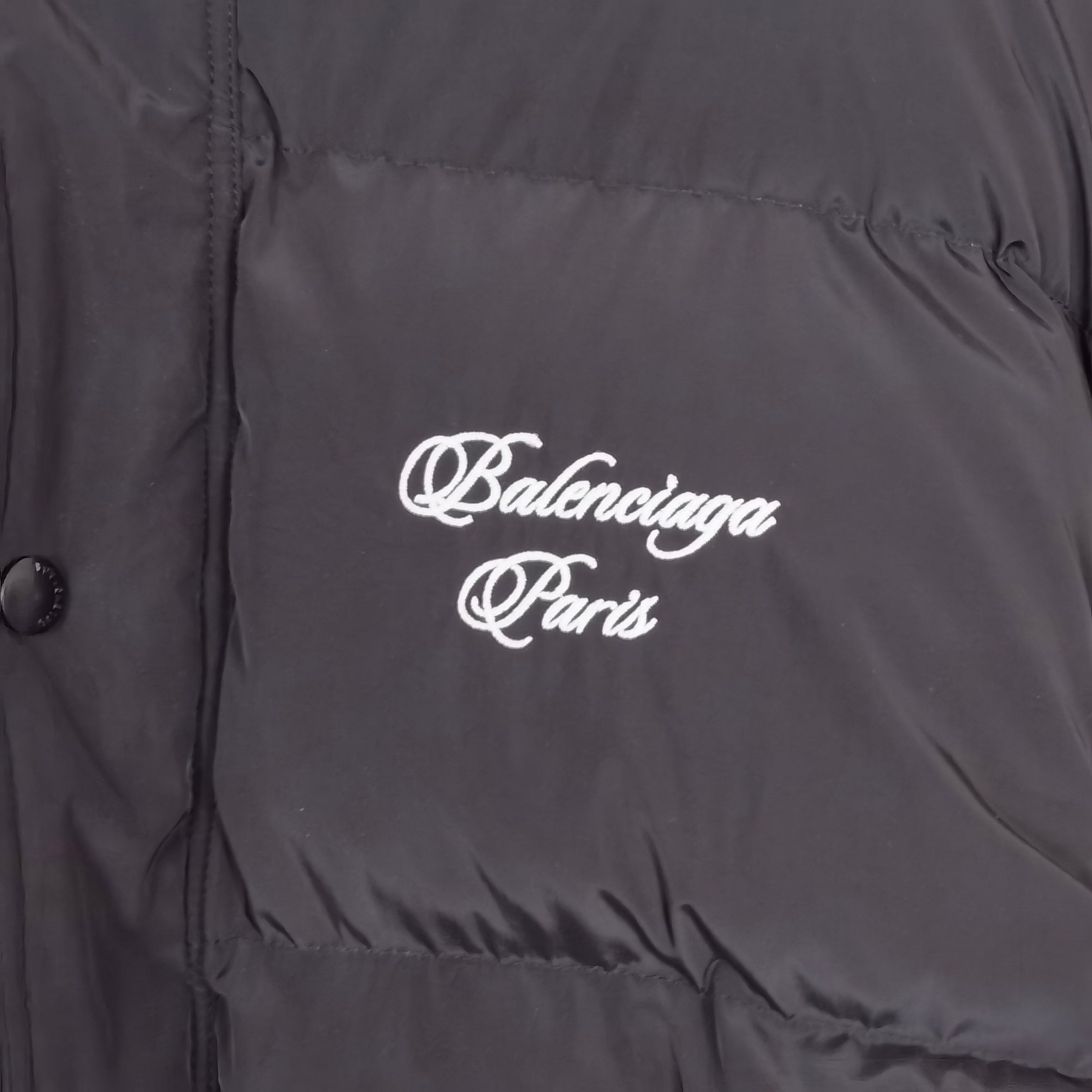 Close-up of dark gray puffer jacket fabric with white Balenciaga Paris chest logo