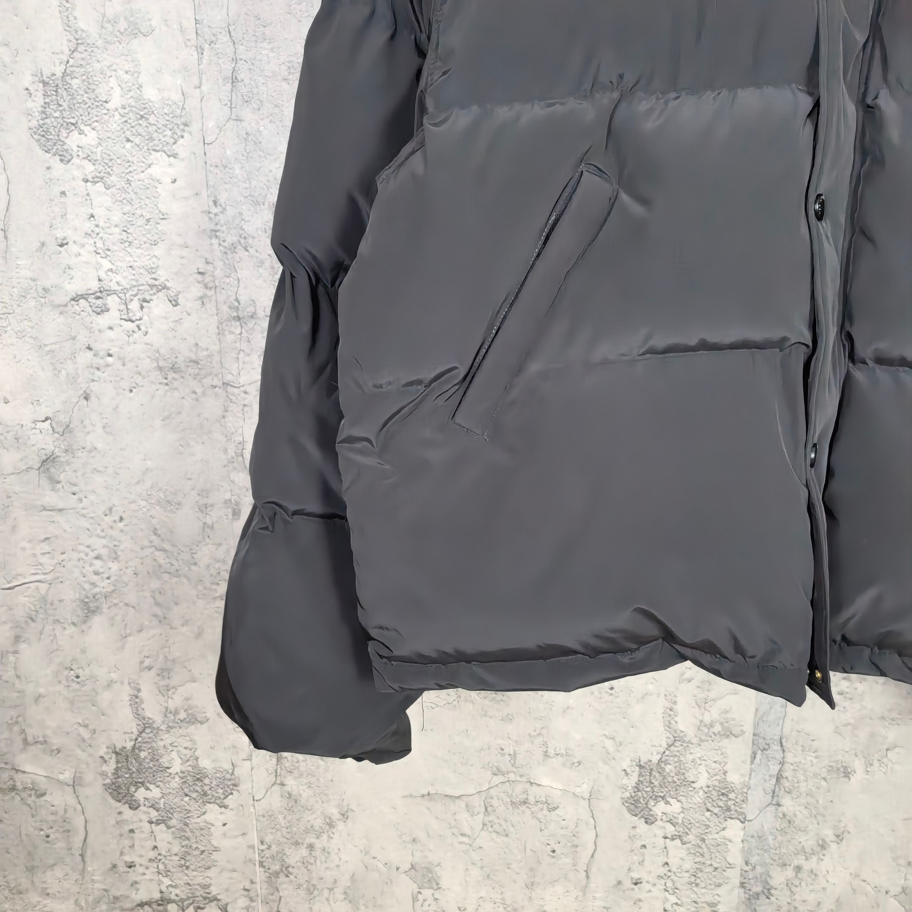 Long puffer jacket in dark gray, front pocket and hem area shown