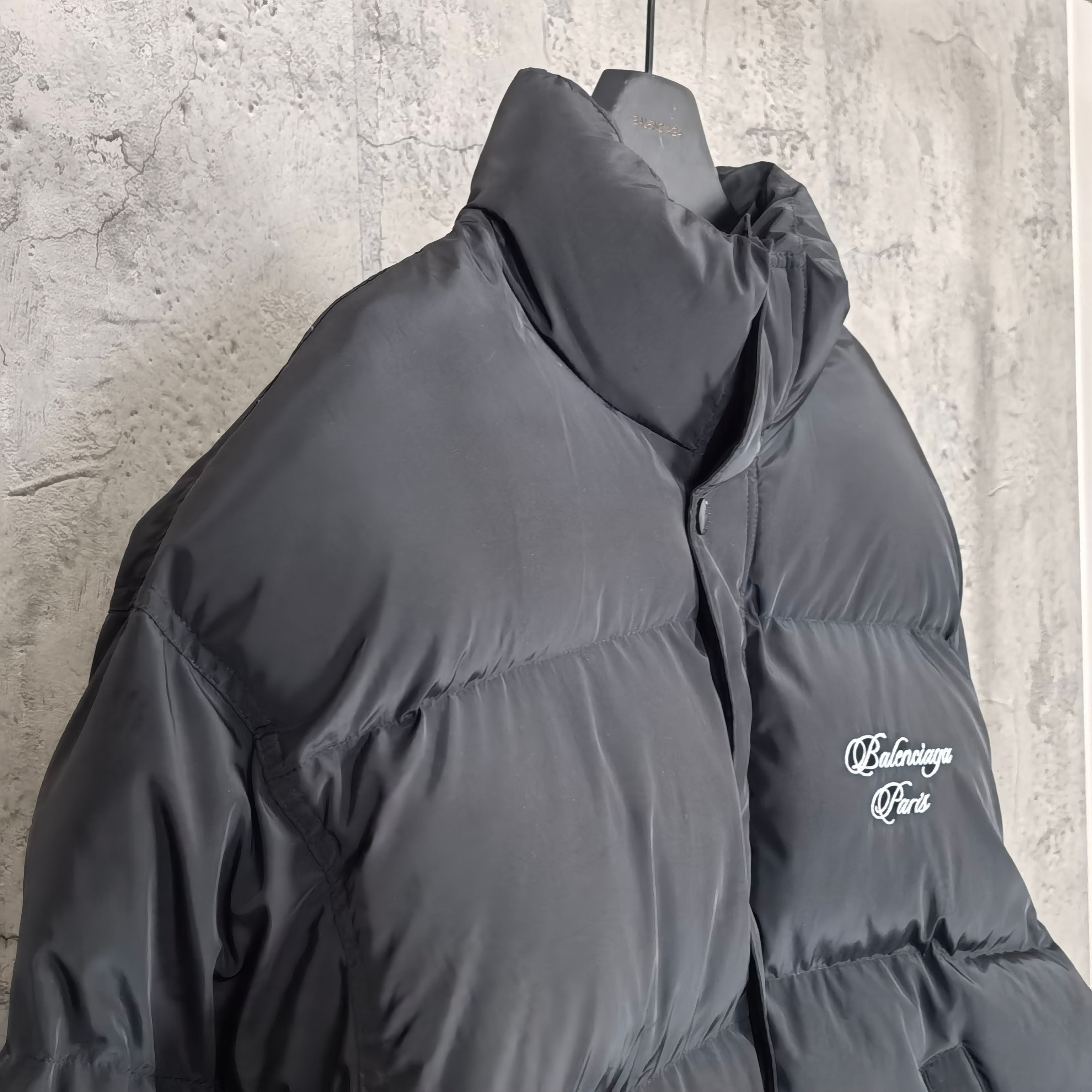 Long hooded puffer jacket in dark gray, side view with chest logo detail