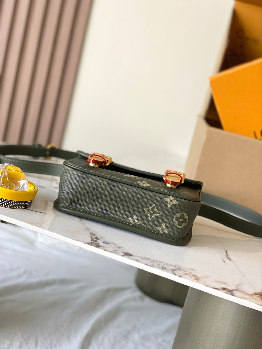 Dark green Louis Vuitton monogram crossbody with flat strap and gold-tone buckle details.