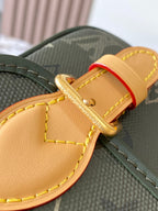 Louis Vuitton crossbody strap detail with tan leather trim and gold buckle on dark green canvas