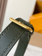 Gold-tone hardware with engraved Louis Vuitton on dark green leather-trimmed strap.