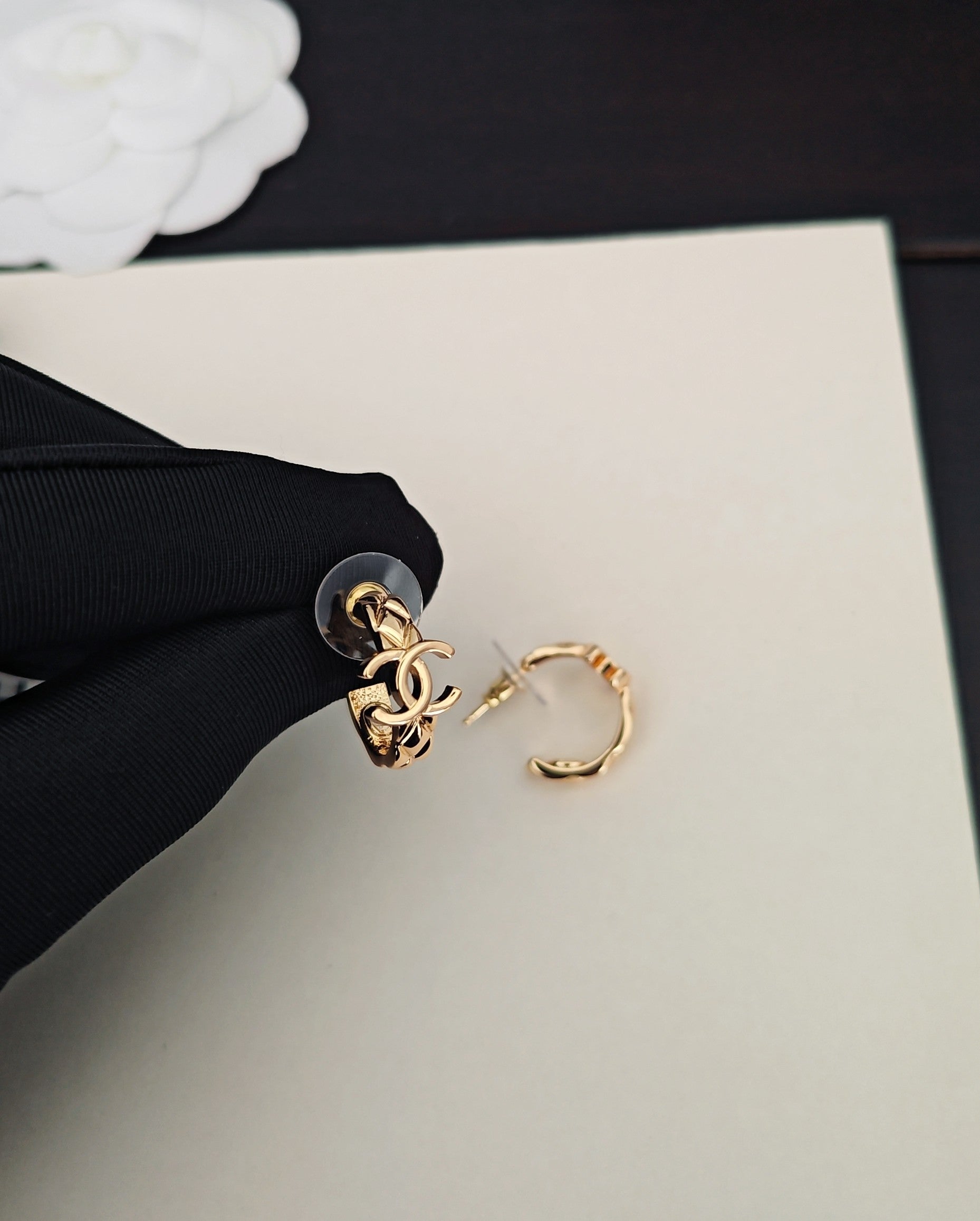 Gold-tone Chanel CC ring beside small hoop earring