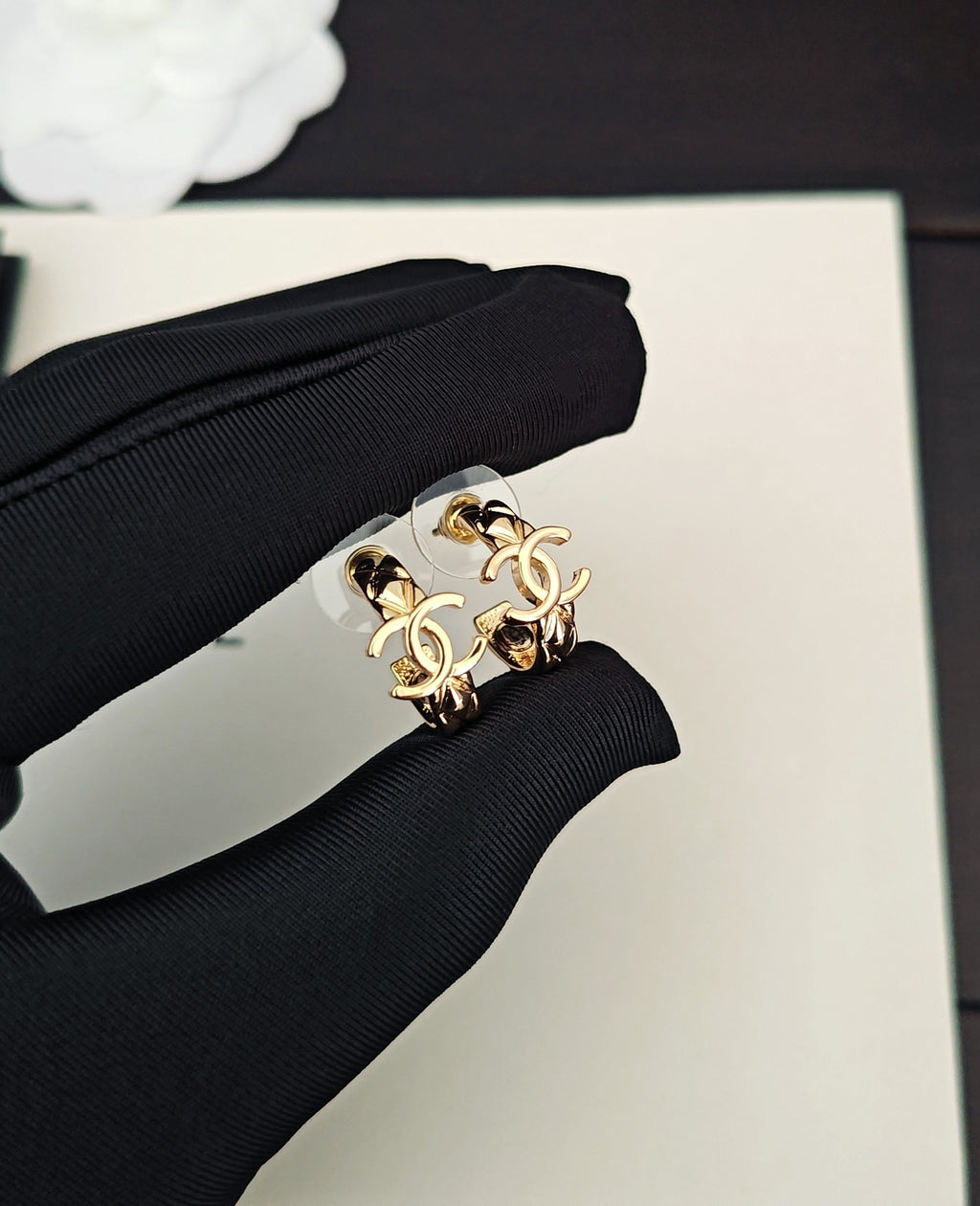 Gold-tone Chanel CC statement ring held in black fabric glove