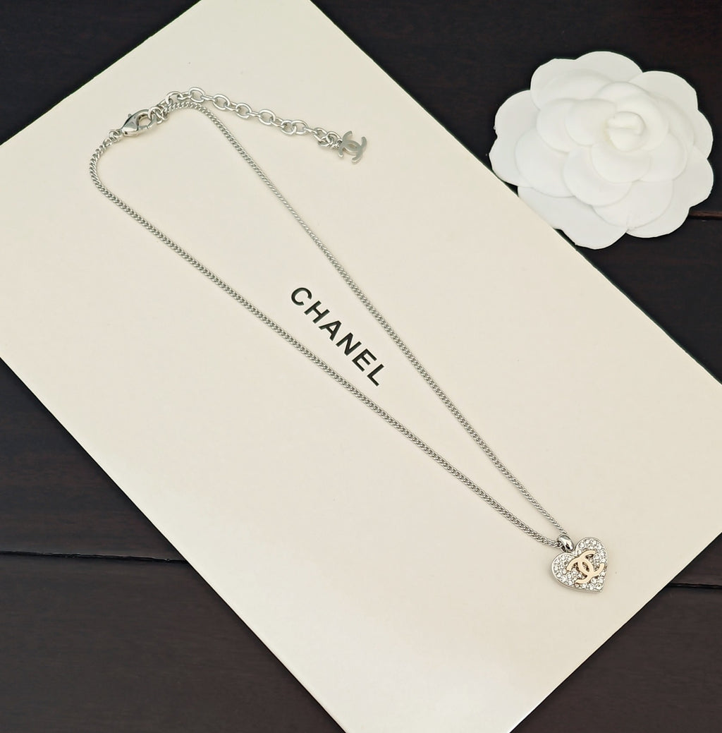 Silver-tone chain necklace with CC heart charm, displayed on a card