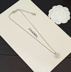 Silver-tone chain necklace with CC heart charm, displayed on a card