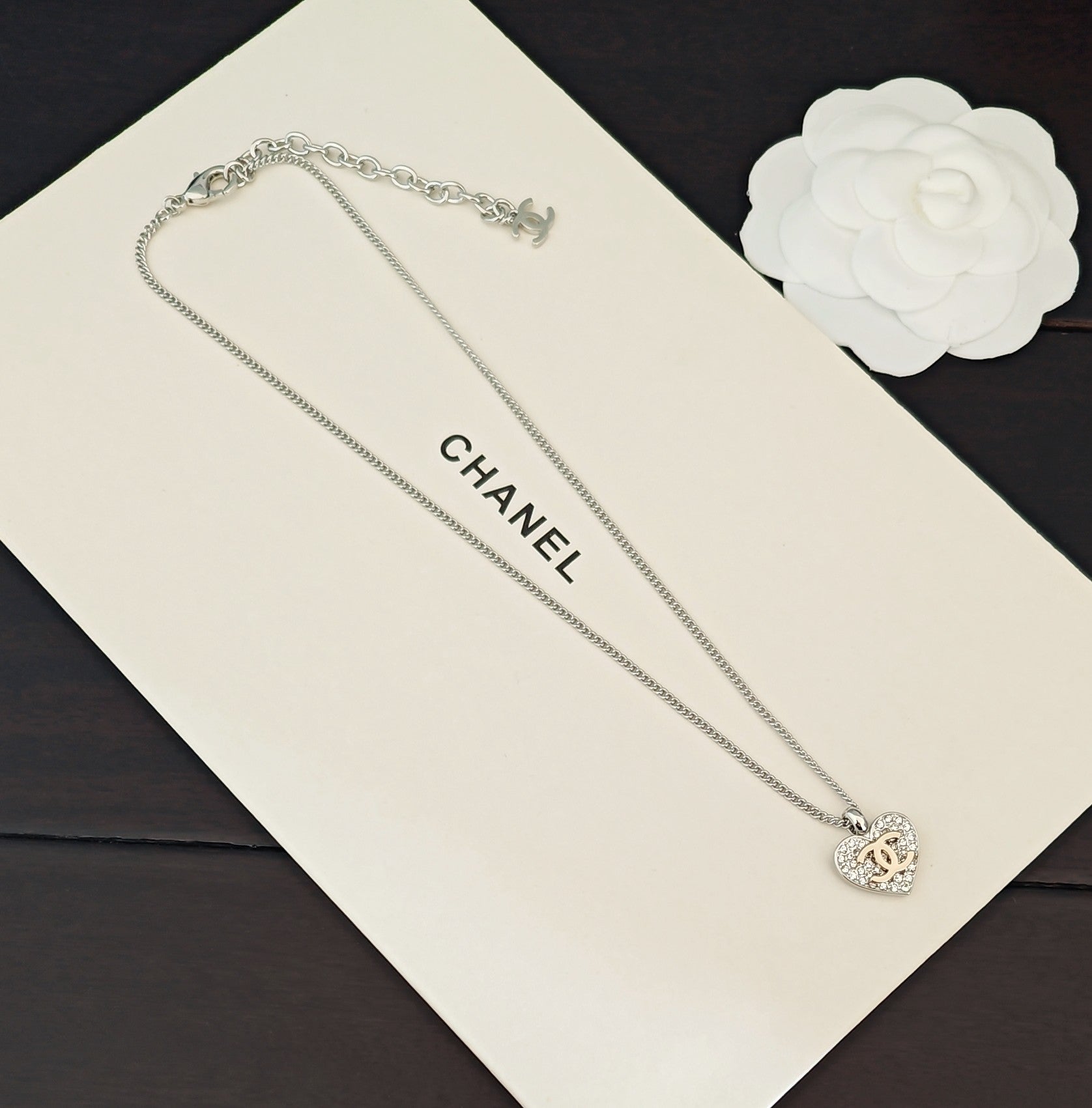 Silver-tone chain necklace with CC heart charm, displayed on a card