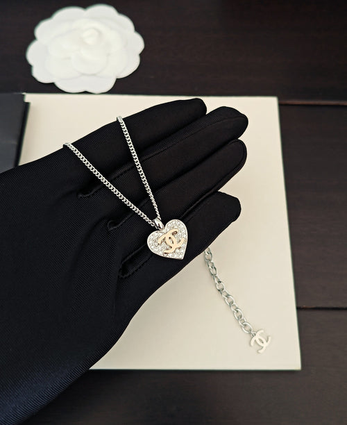 Silver-tone chain necklace with heart pendant on black gloves