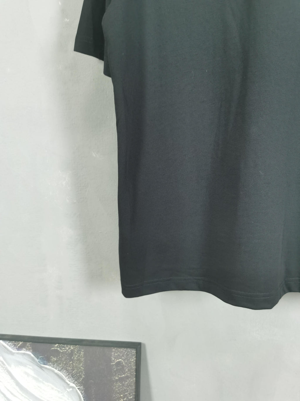 Dark crewneck T-shirt back view with straight hem and no visible graphics