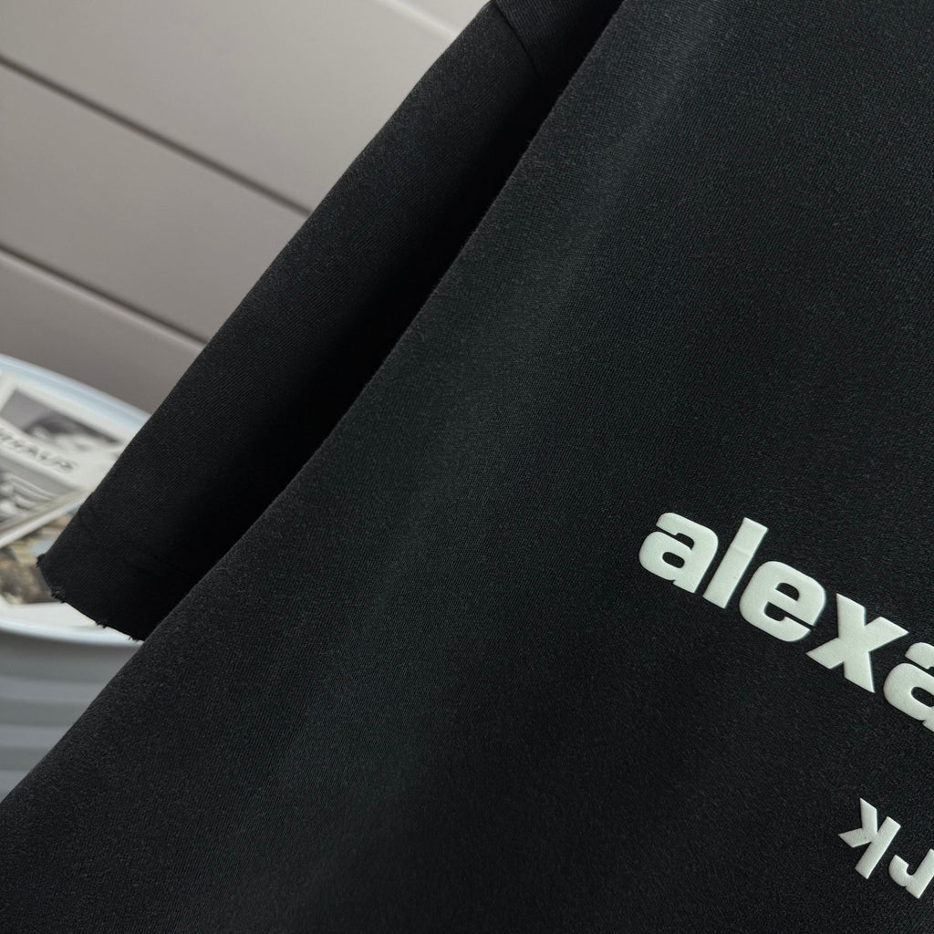 Detail view of dark black short-sleeve T-shirt sleeve and side graphic text