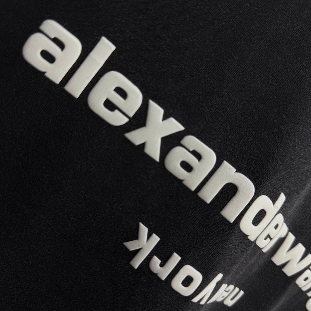 Side close-up of alexanderwang logo on a dark black short-sleeve T-shirt