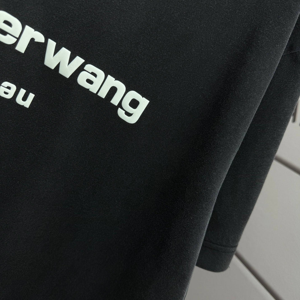 Close-up of dark black T-shirt fabric with partial alexanderwang logo lettering