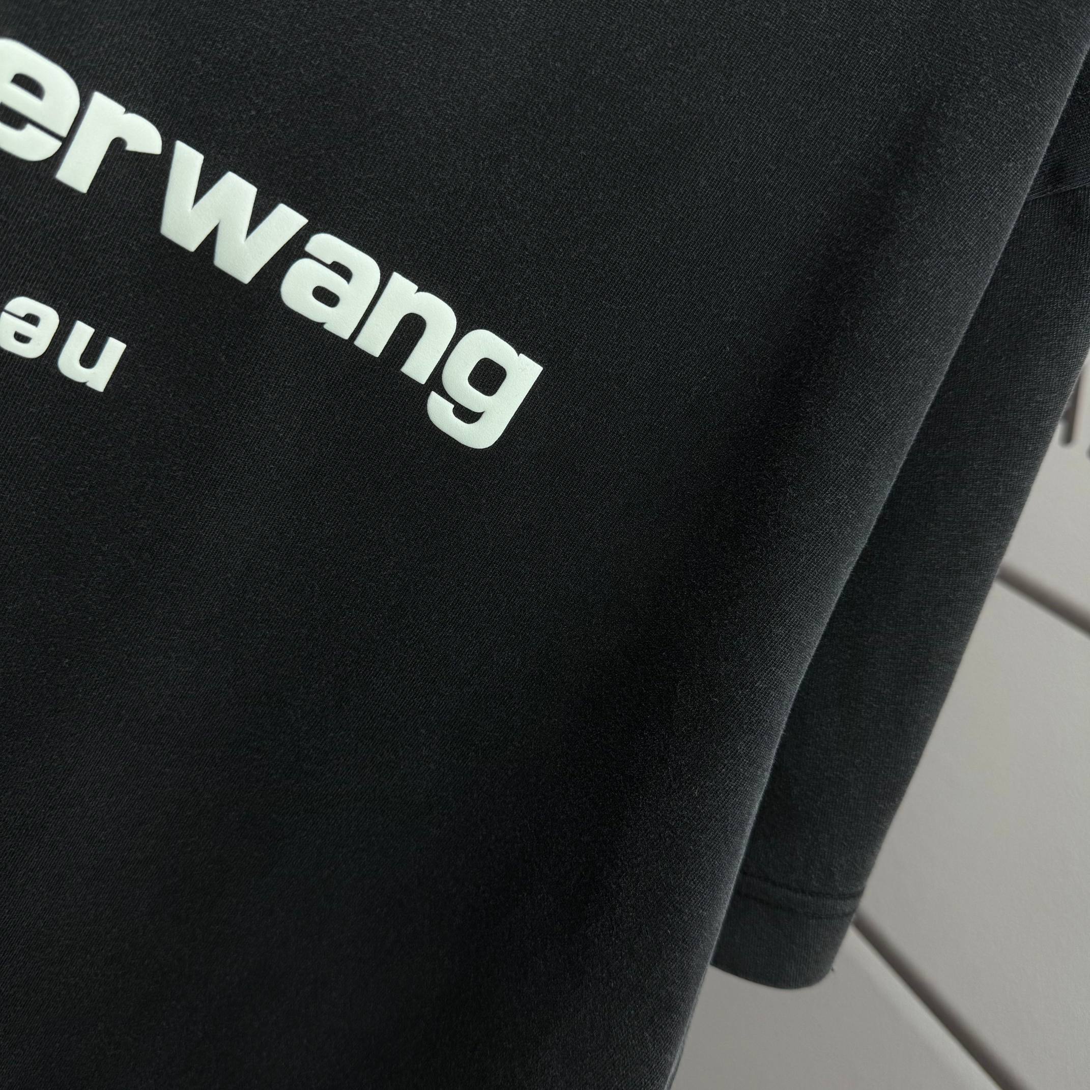 Close-up of dark black T-shirt fabric with partial alexanderwang logo lettering