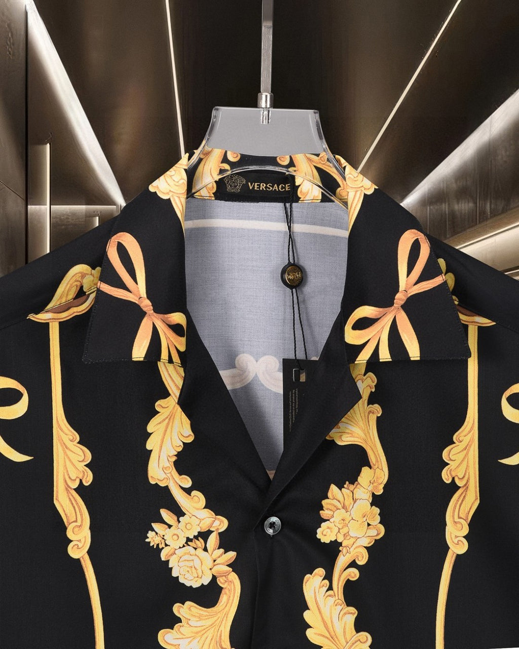 Black Versace shirt with gold bow and floral scroll motifs, front collar visible