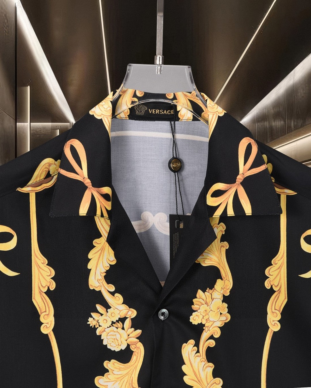 Black Versace shirt with gold bow and floral scroll motifs, front collar visible