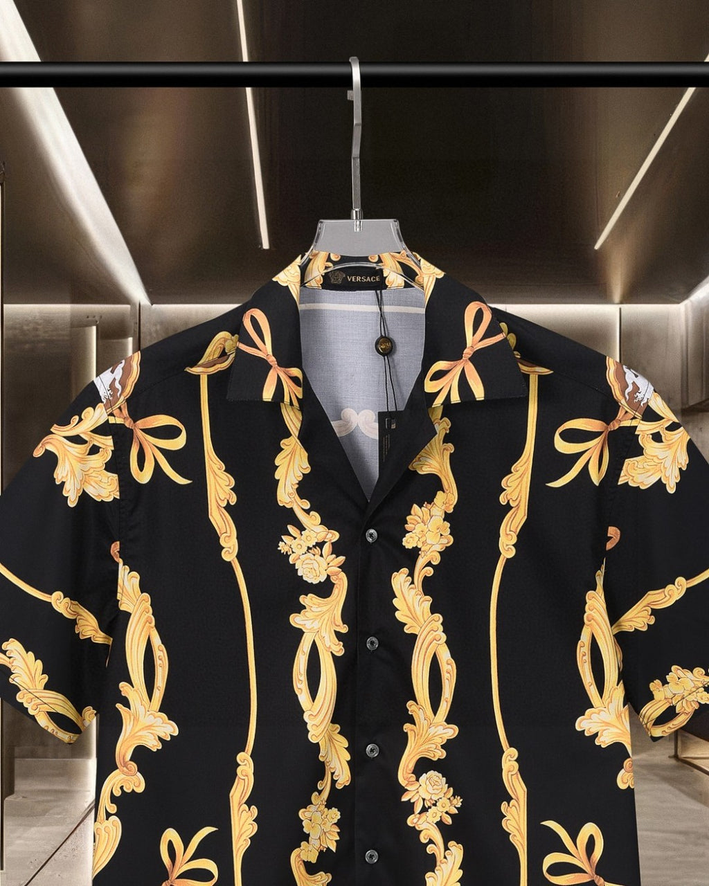 Black short-sleeve shirt with notched collar and gold baroque ornament across front