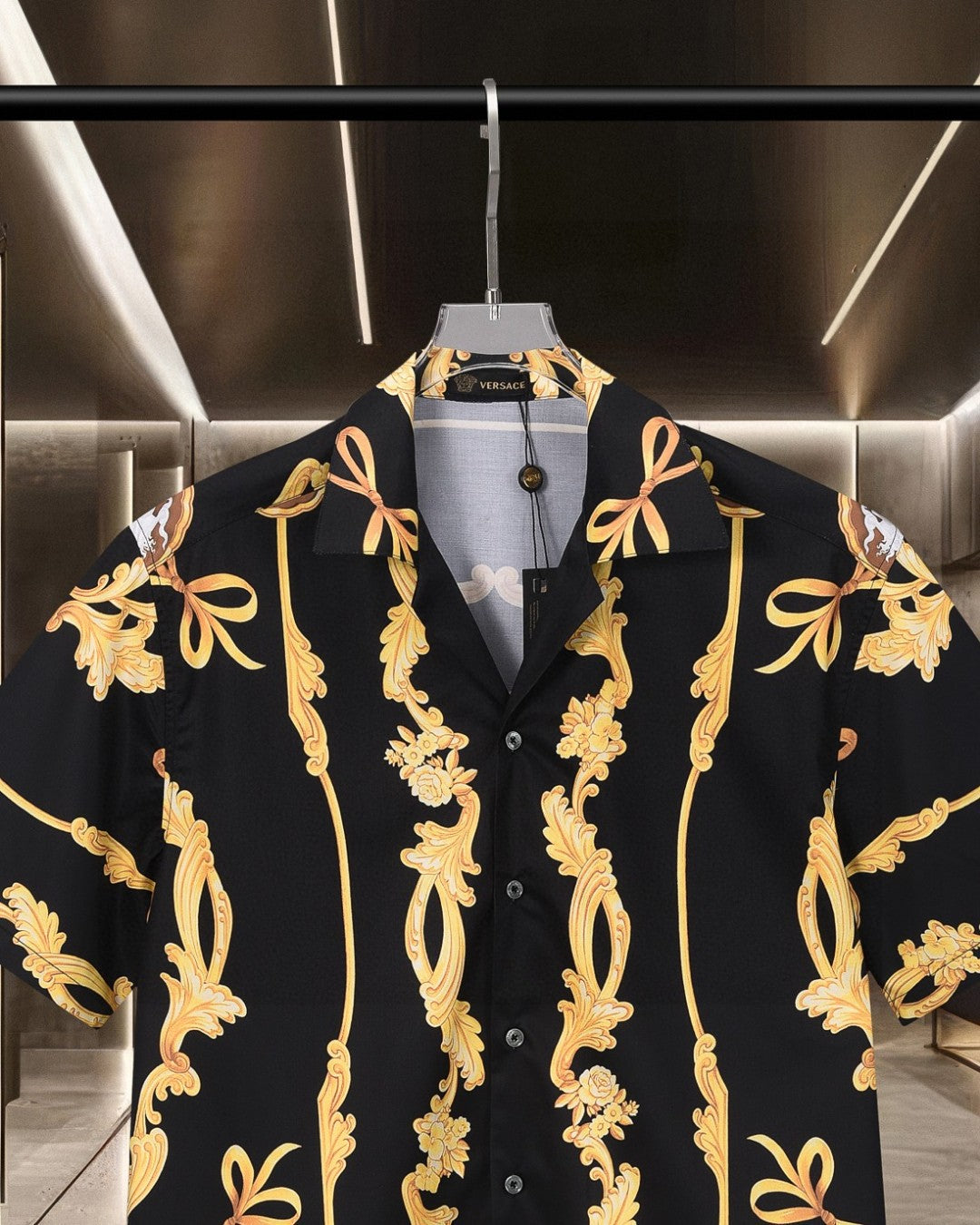 Black short-sleeve shirt with notched collar and gold baroque ornament across front