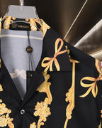 Black shirt detail at chest with gold floral scroll design and draped bow motif