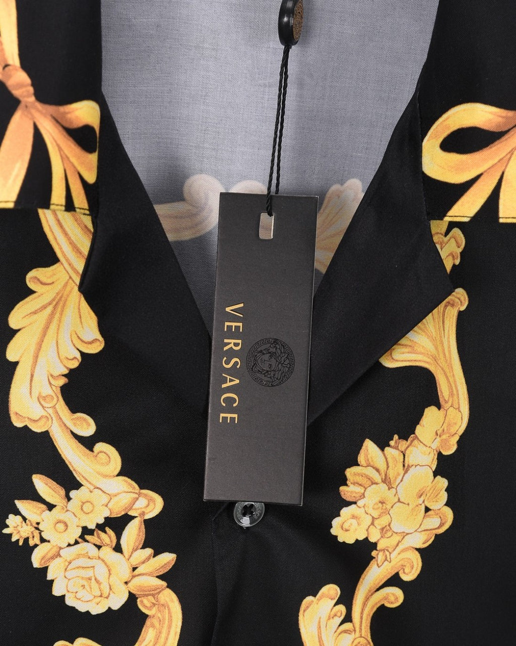 Black shirt with gold floral scroll print and VERSACE hang tag on neckline