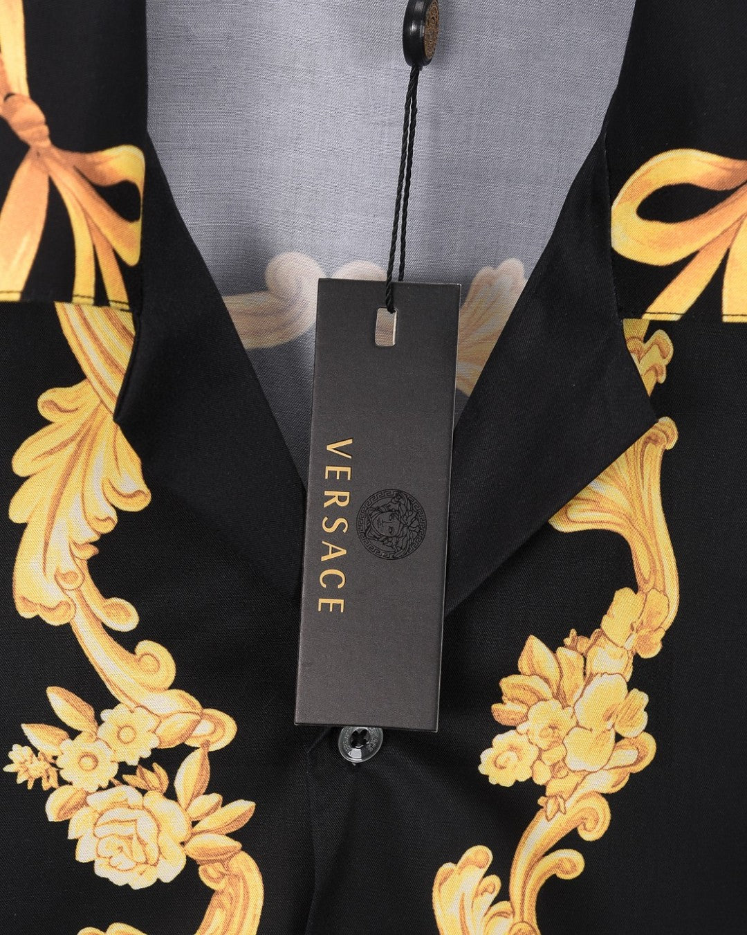 Black shirt with gold floral scroll print and VERSACE hang tag on neckline