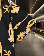 Black shirt side detail with large gold scroll pattern and ribbon-like accents
