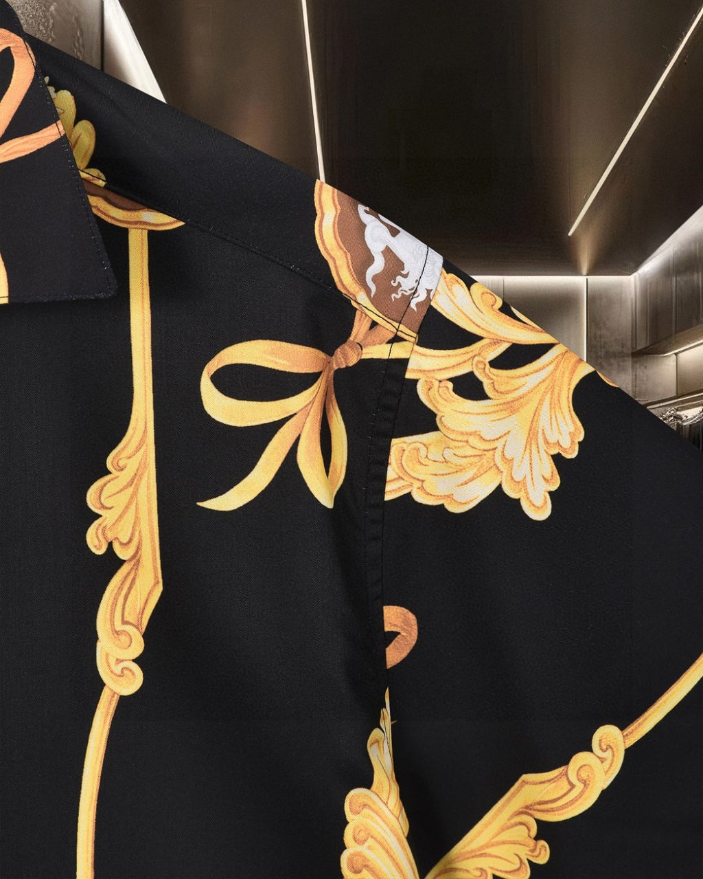 Black shirt sleeve detail with gold bow and floral ornament motif
