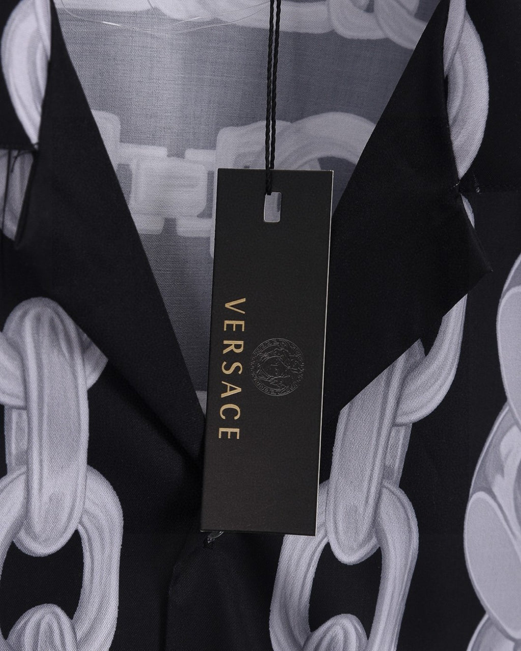 Versace branded hang tag on black shirt with white chain-link print