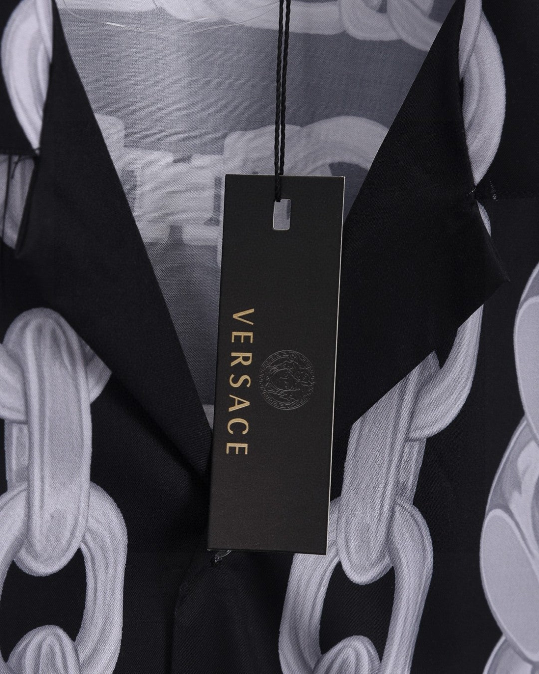 Versace branded hang tag on black shirt with white chain-link print