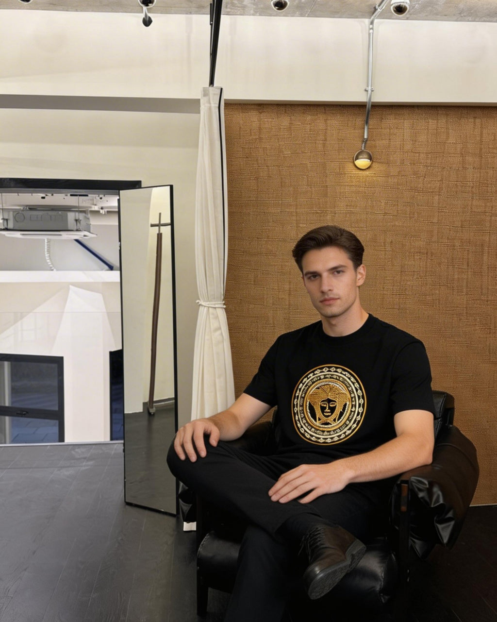 Black crew-neck T-shirt with gold medallion Medusa-style logo on the chest