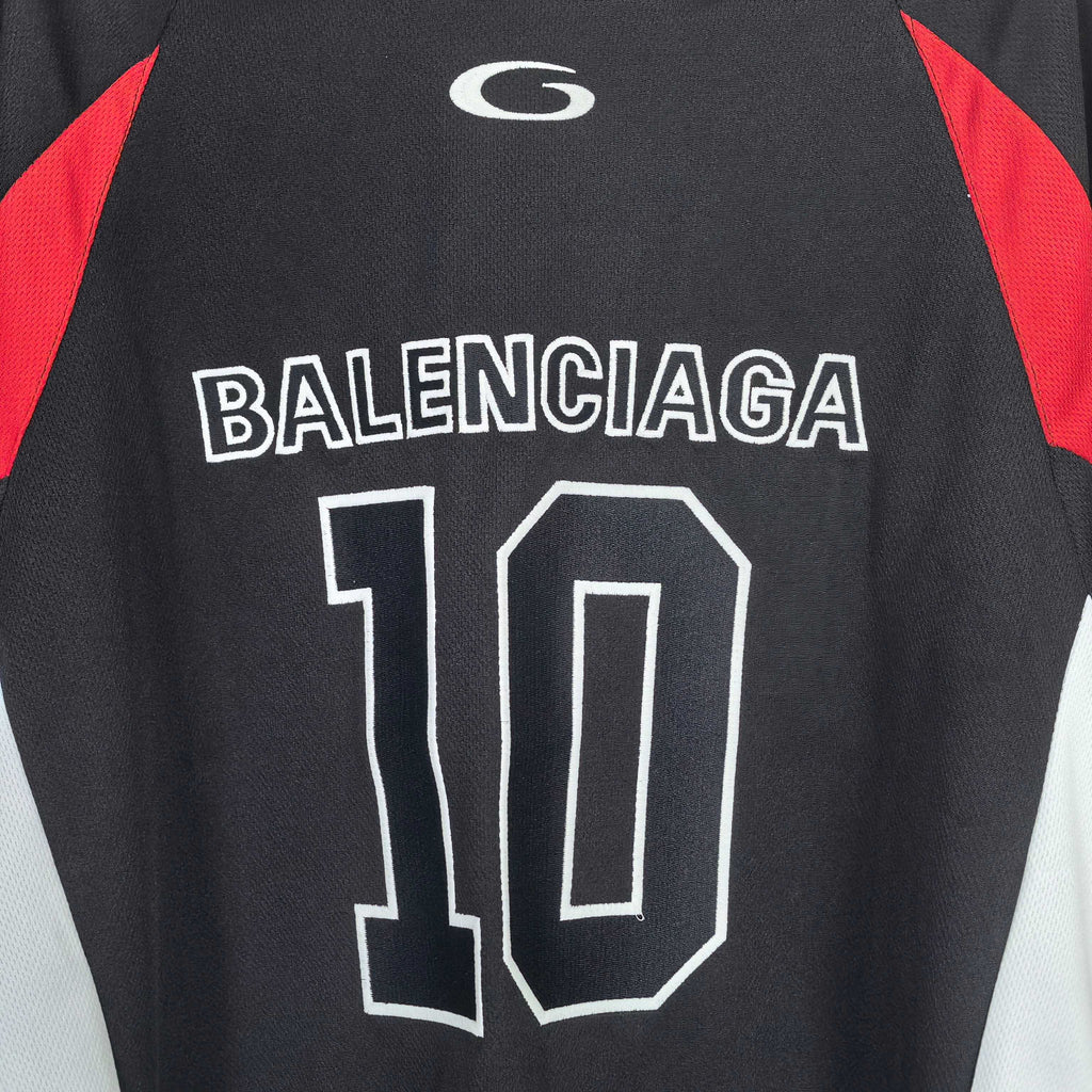 Black jersey graphic close-up: BALENCIAGA 10 print with red sleeve panel accents