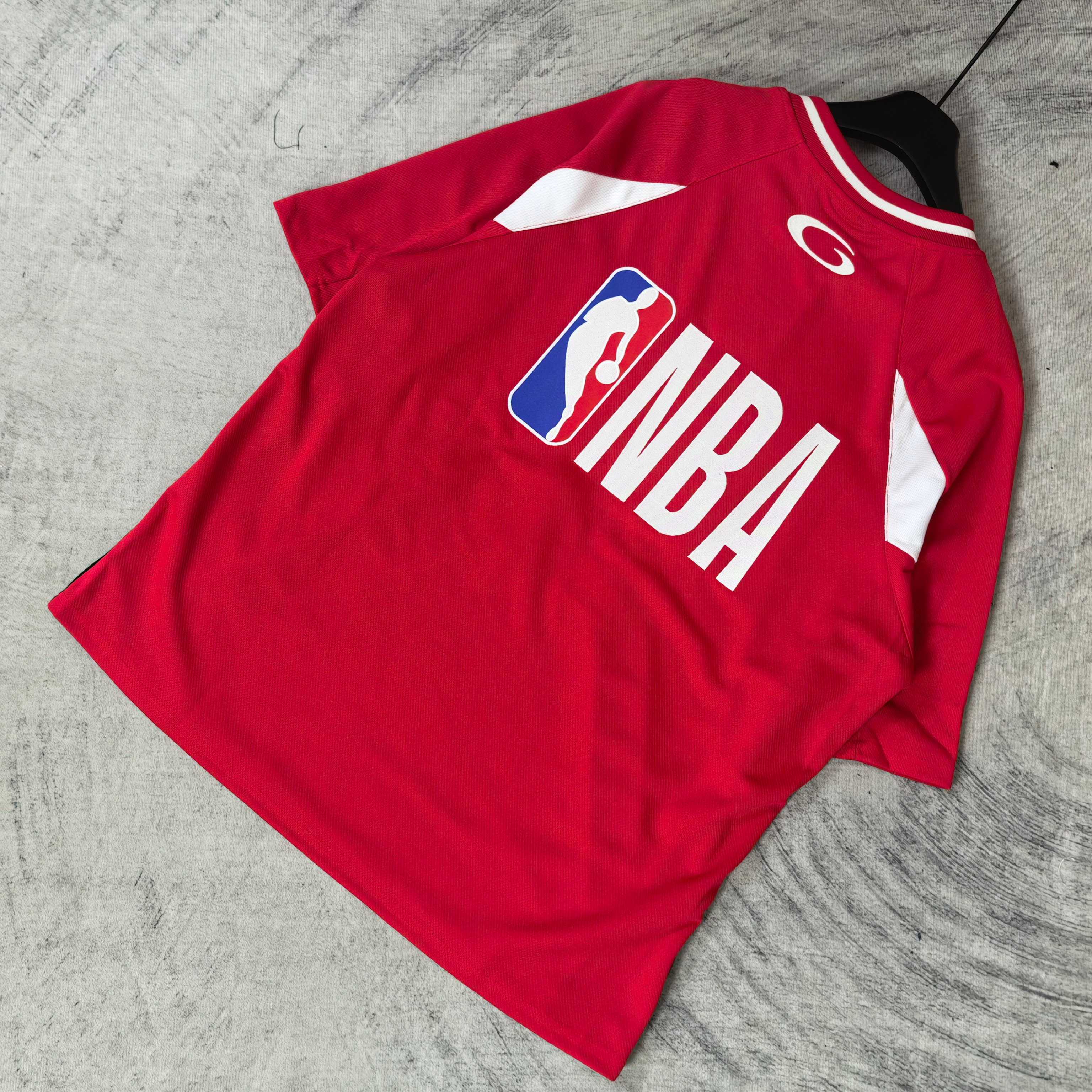 Red short-sleeve jersey laid flat with NBA back logo and white shoulder stripes