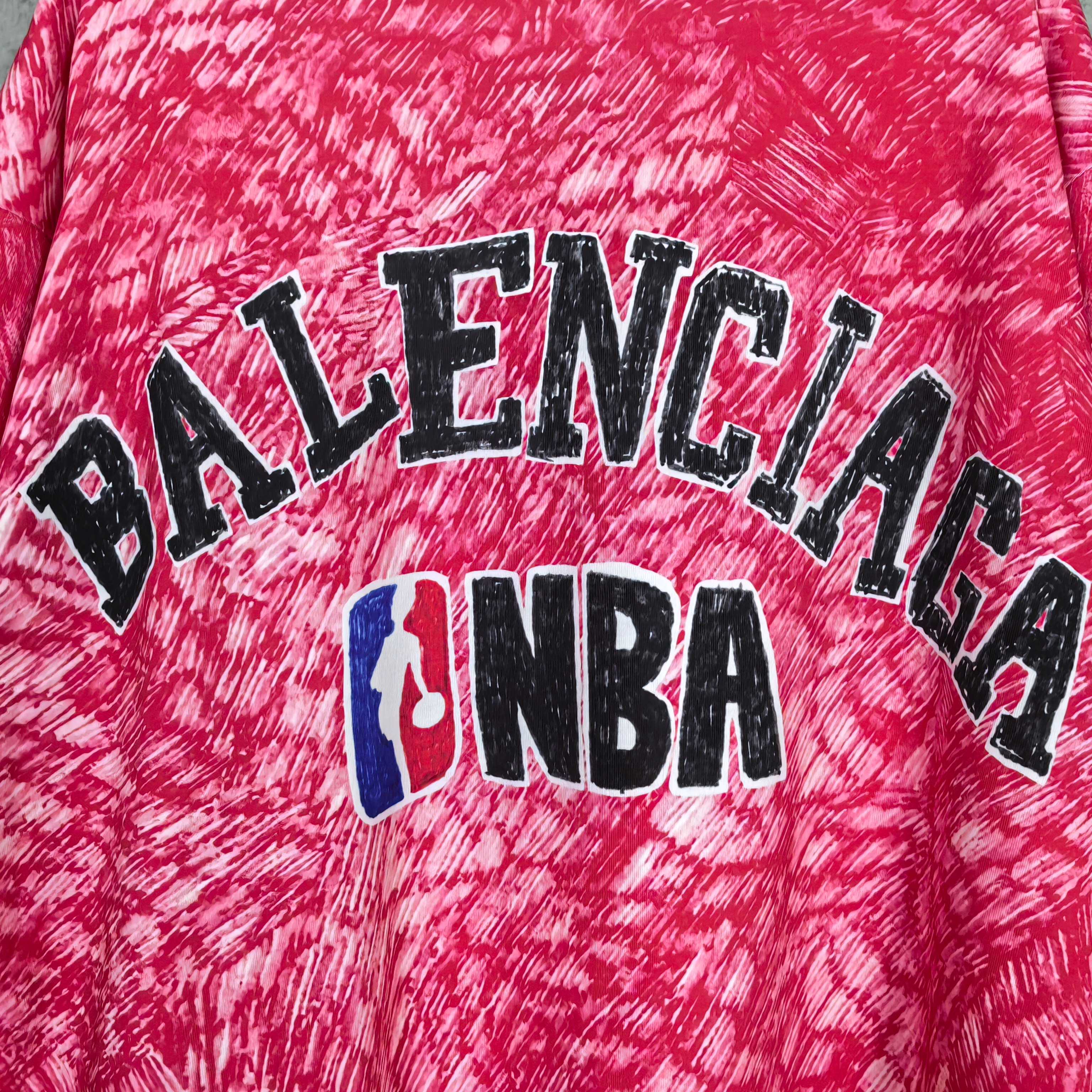 Balenciaga T-shirt print close-up: BALENCIAGA text and NBA emblem on red