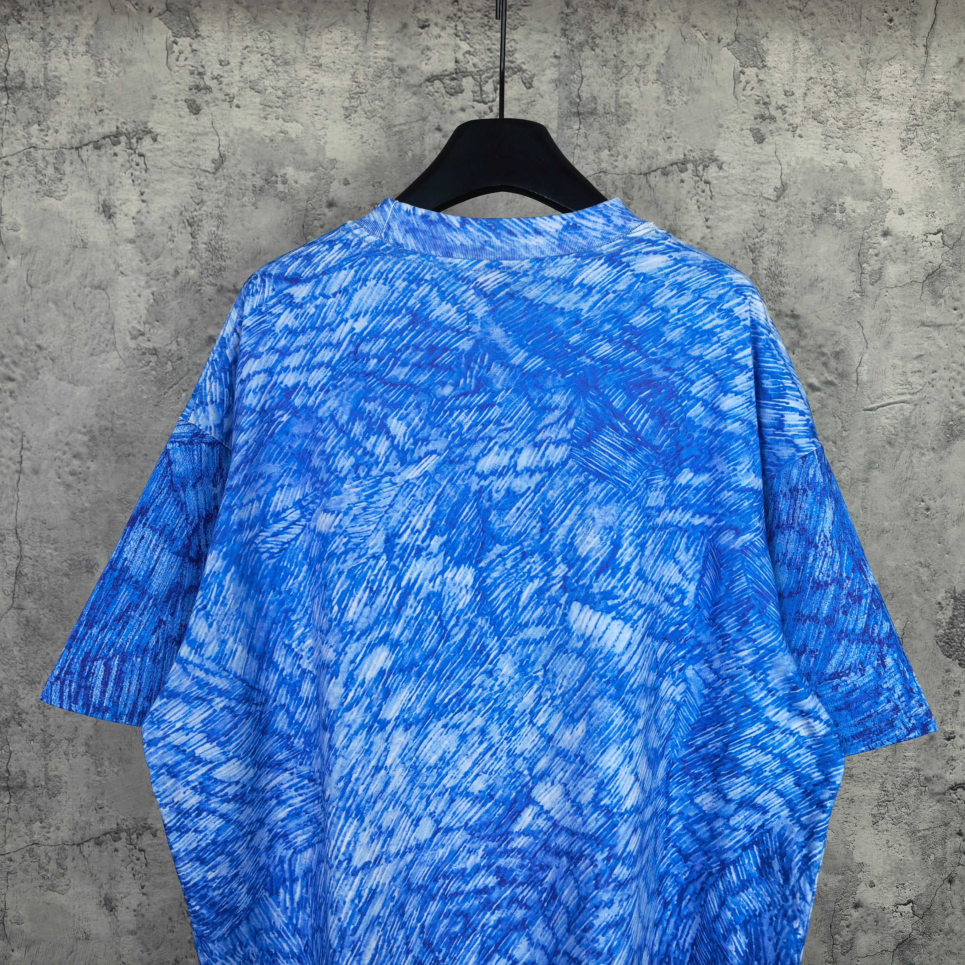 Blue short-sleeve graphic T-shirt, close back view with all-over textured pattern.