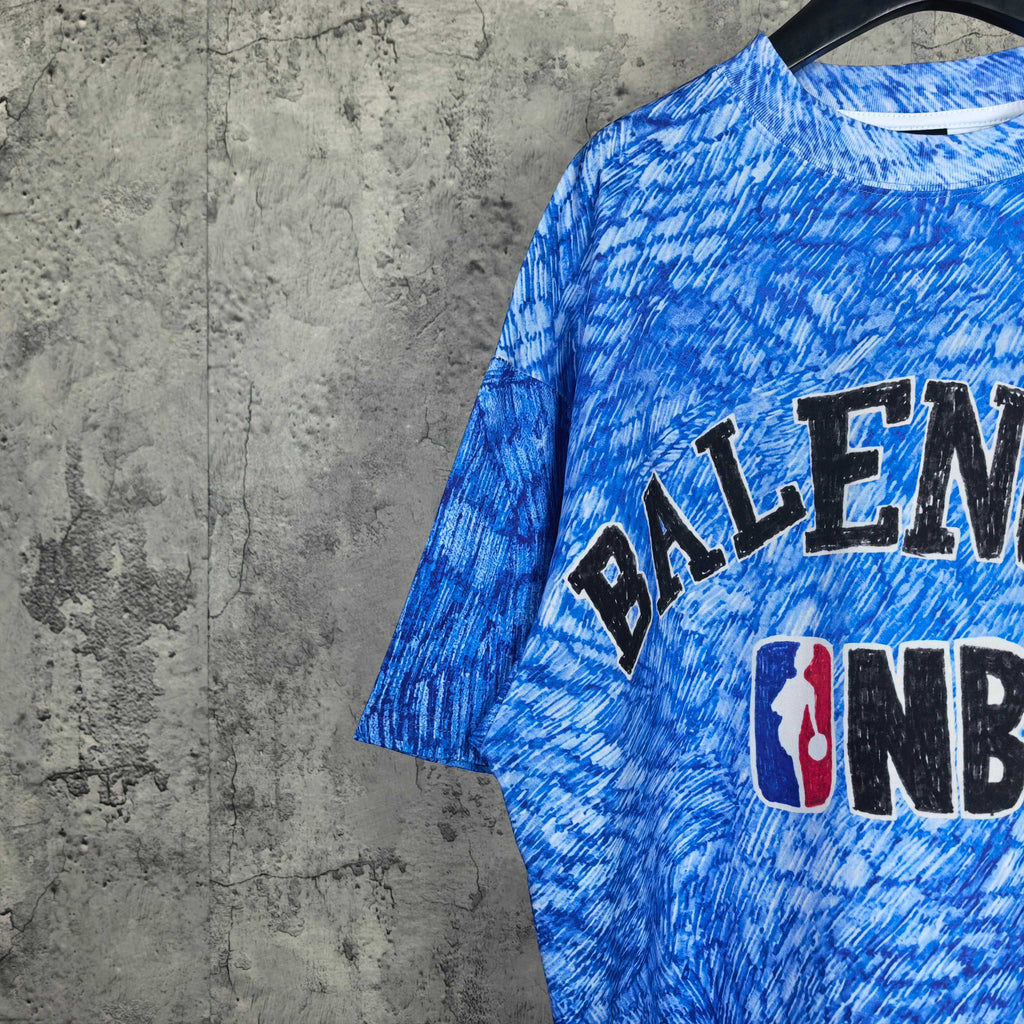Partial view of blue short-sleeve T-shirt with Balenciaga text and NBA logo.