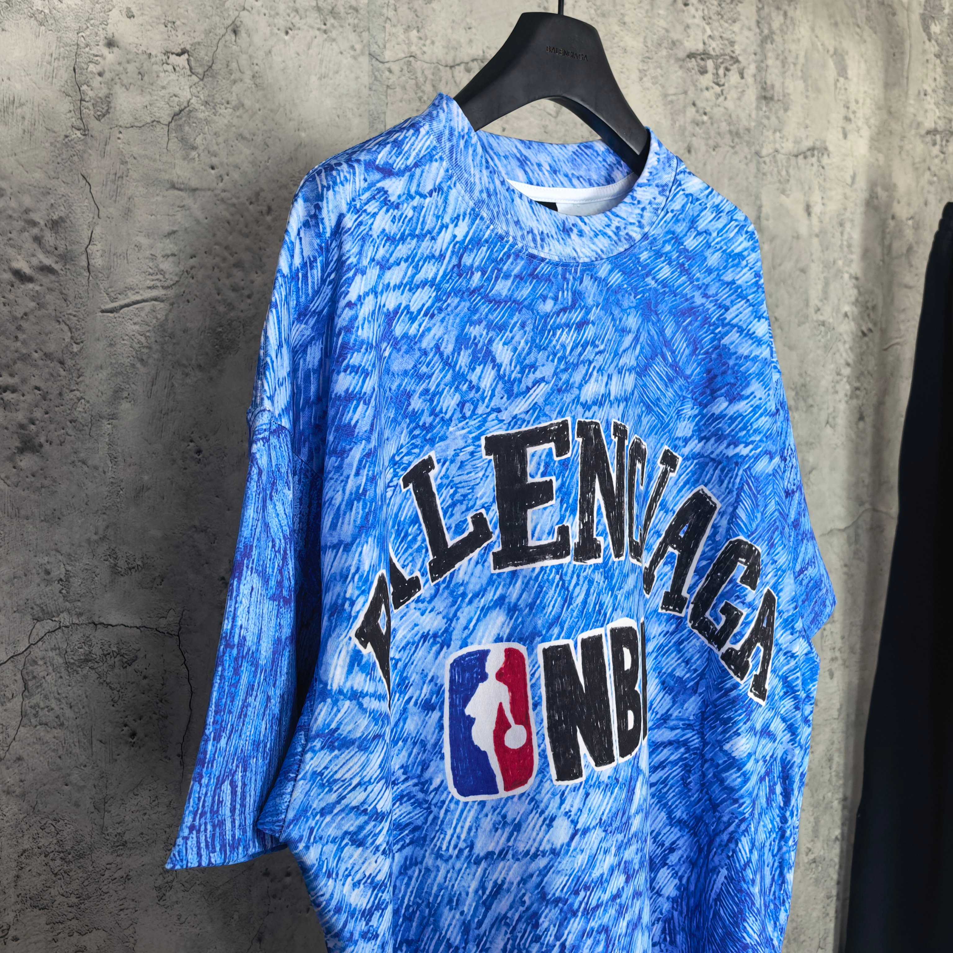 Blue short-sleeve graphic T-shirt, front view with Balenciaga text and NBA logo.