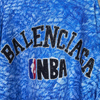 Close-up of blue T-shirt chest graphic: Balenciaga text and NBA logo.