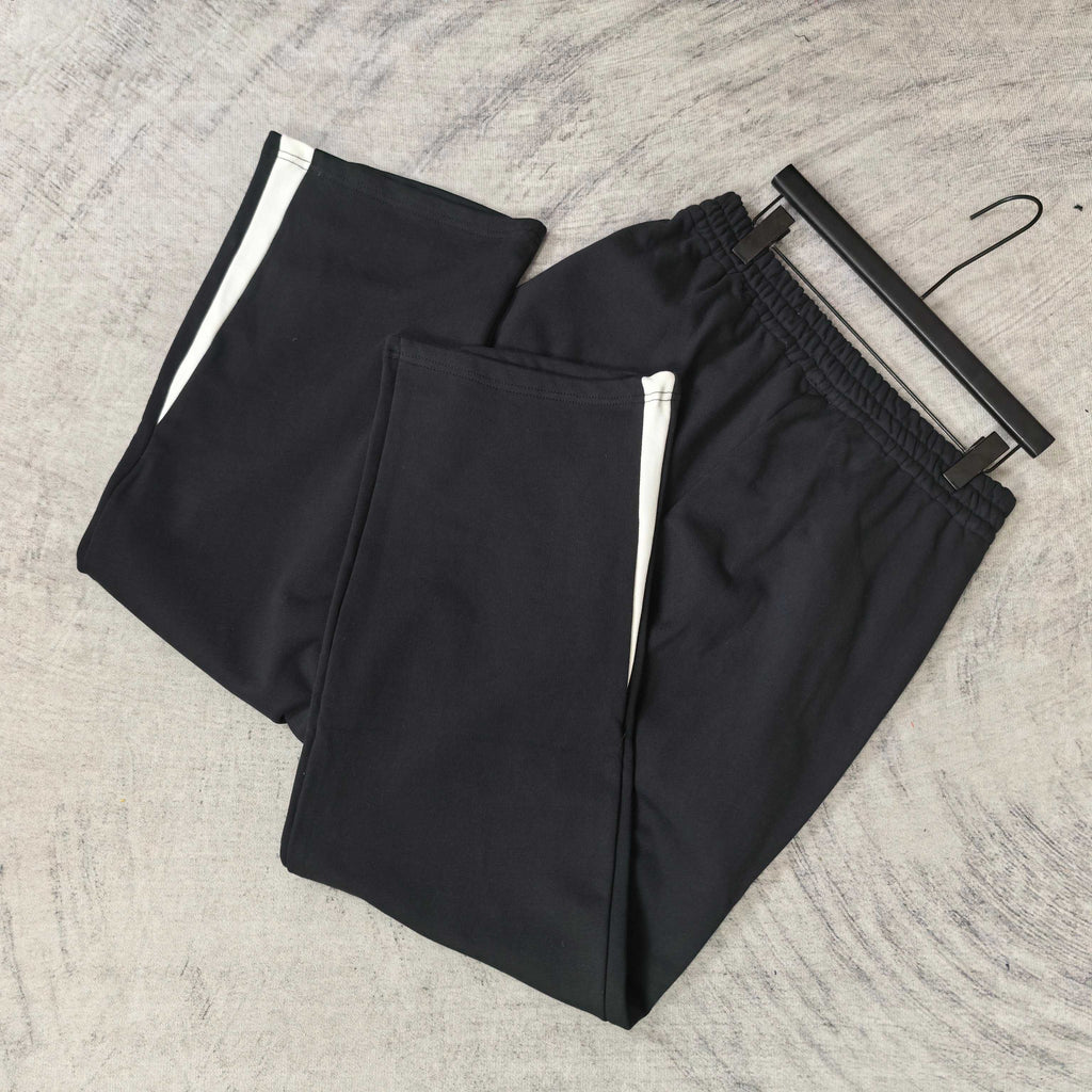 Pair of black track pants with white side stripes and elastic cuffs