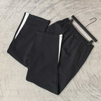 Pair of black track pants with white side stripes and elastic cuffs
