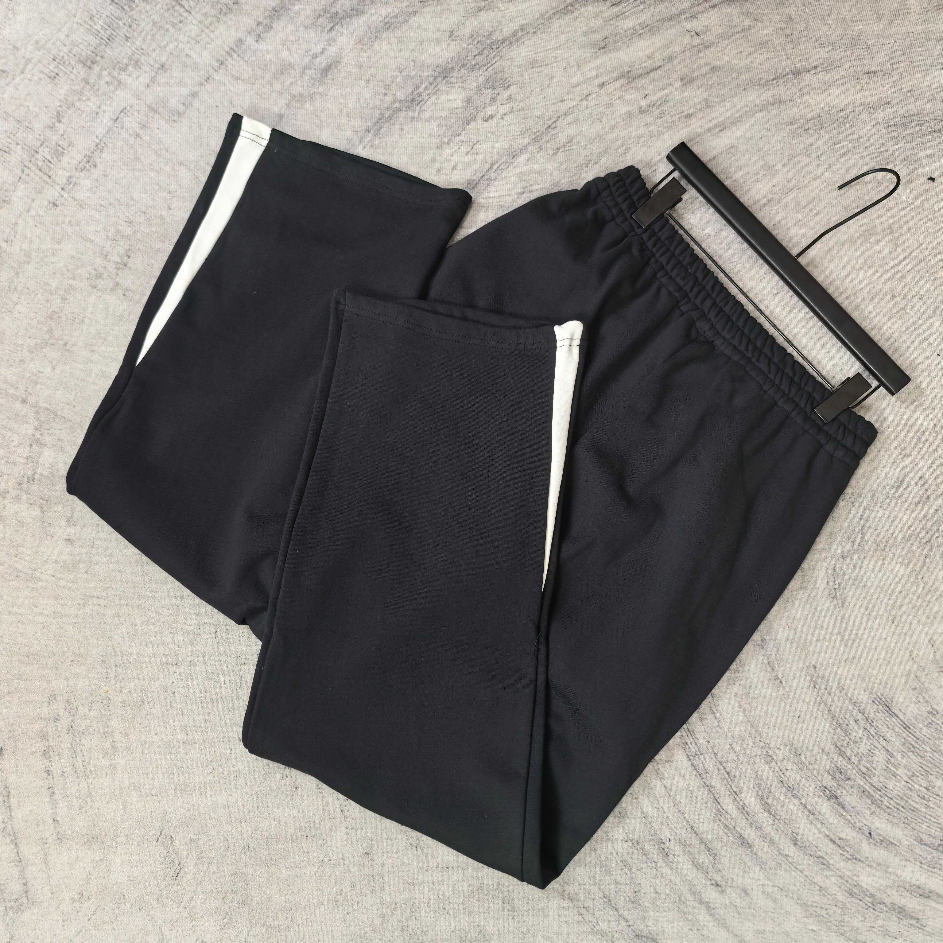 Pair of black track pants with white side stripes and elastic cuffs