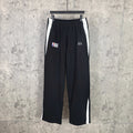 Black track pants with white side stripes, elastic waistband, NBA and Balenciaga logos