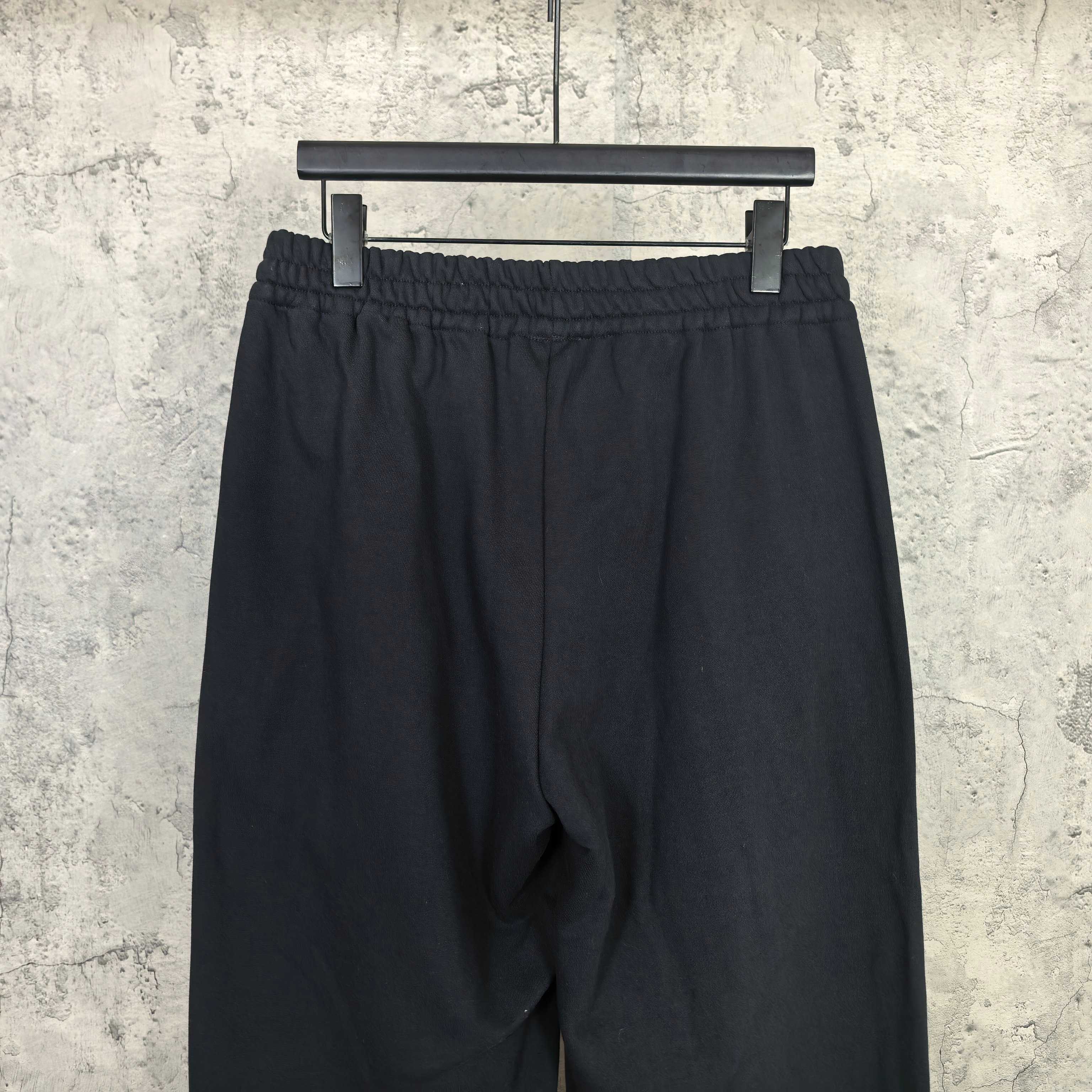 Black track pants back view, elastic waistband and roomy leg fit