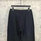 Black track pants with elastic waistband and textured fabric surface